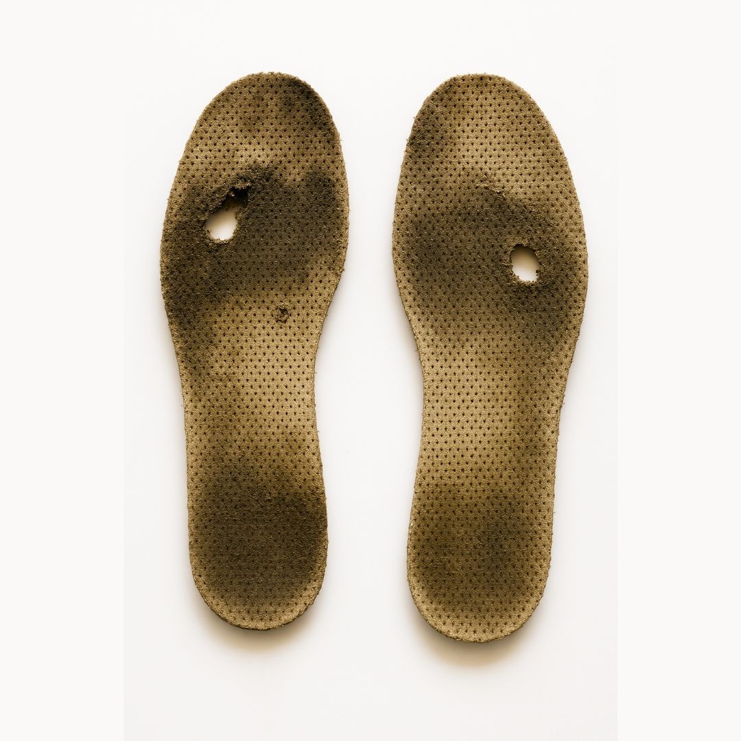 Bild på ett par gamla och slitna skoinlägg med hål och smutsfläckar, som illustrerar behovet av att byta till nya, stötdämpande och hygieniska CloudTech Comfort-inlägg från Nordic Rehab för bättre komfort, stöd och fot­hälsa.