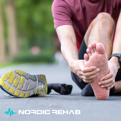 Person sitter på en löpbana och håller sig om foten efter löpning, med skon avtagen bredvid. Bilden visar vikten av rätt skor för att förebygga fotsmärta och överbelastning — något NEO Sport barfotaskor från Nordic Rehab hjälper till att motverka genom naturlig rörelse och starkare fotmuskulatur.